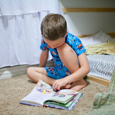 jeune garçon lisant un livre dans sa chambre